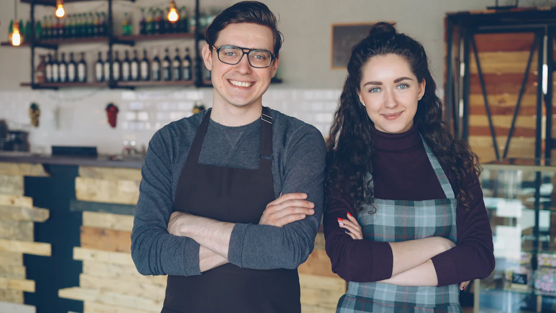 Zwei Inhaber stehen mit verschränkten Armen in ihrem Café